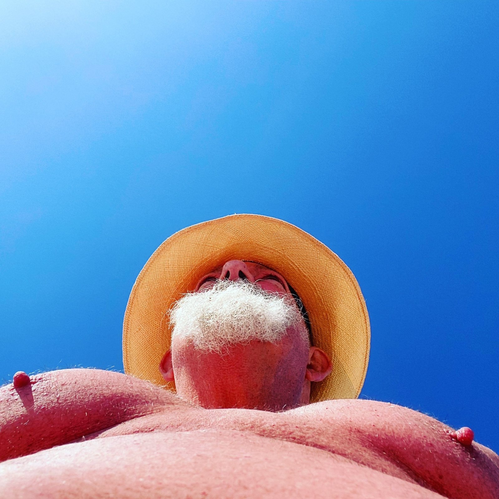 Hypnodaddy (Malehypnosis) in a straw hat under a blue sky, seen from below